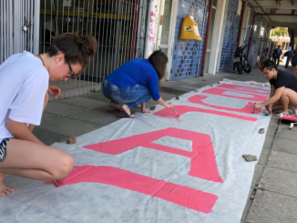 Estudantes pintam cartaz 'Educação Resiste'.