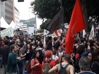 Na foto, manifestantes passam com cartazes, faixas e bandeiras na Marcha pela Educação e Ciência em frente a Catedral de Florianópolis.