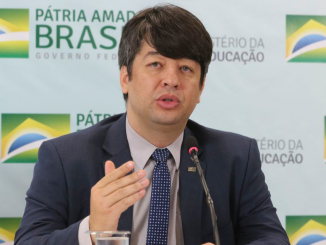 O Secretário do MEC, Arnaldo Barbosa de Lima Junior, em frente ao fundo com padrão "Pátria Amada Brasil", do Governo Federal