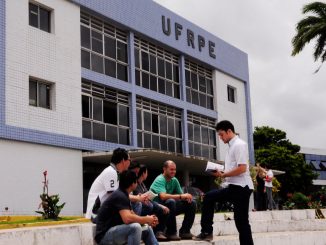 No fundo da imagem um dos prédios da UFRPE e no primeiro plano um grupo de alunos conversando.