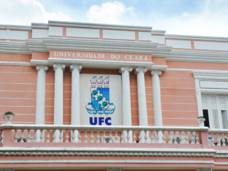 Fachada de um dos prédio da UFC. O prédio tem arquitetura mais antiga, cores rosa e detalhes em branco.