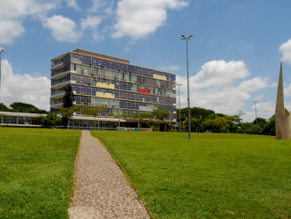Prédio da reitoria da UFMG com um gramado no primeiro plano da foto.